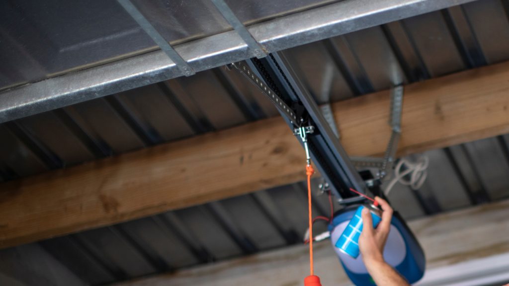 A homeowner spraying lithium grease on the opener chain