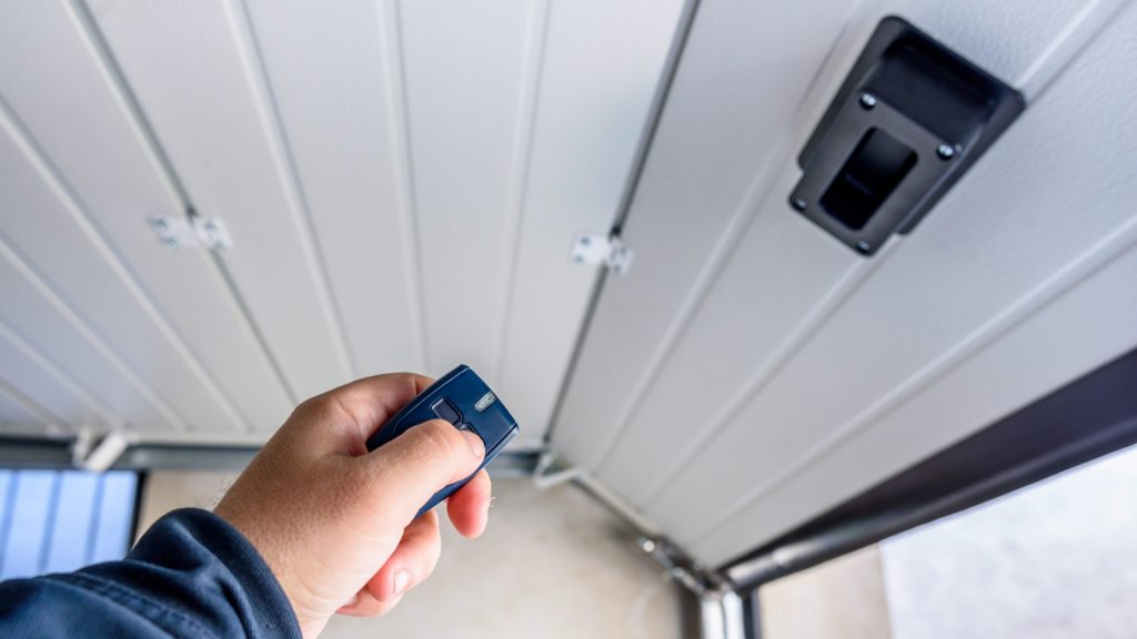 A user opening a garage door using the remote