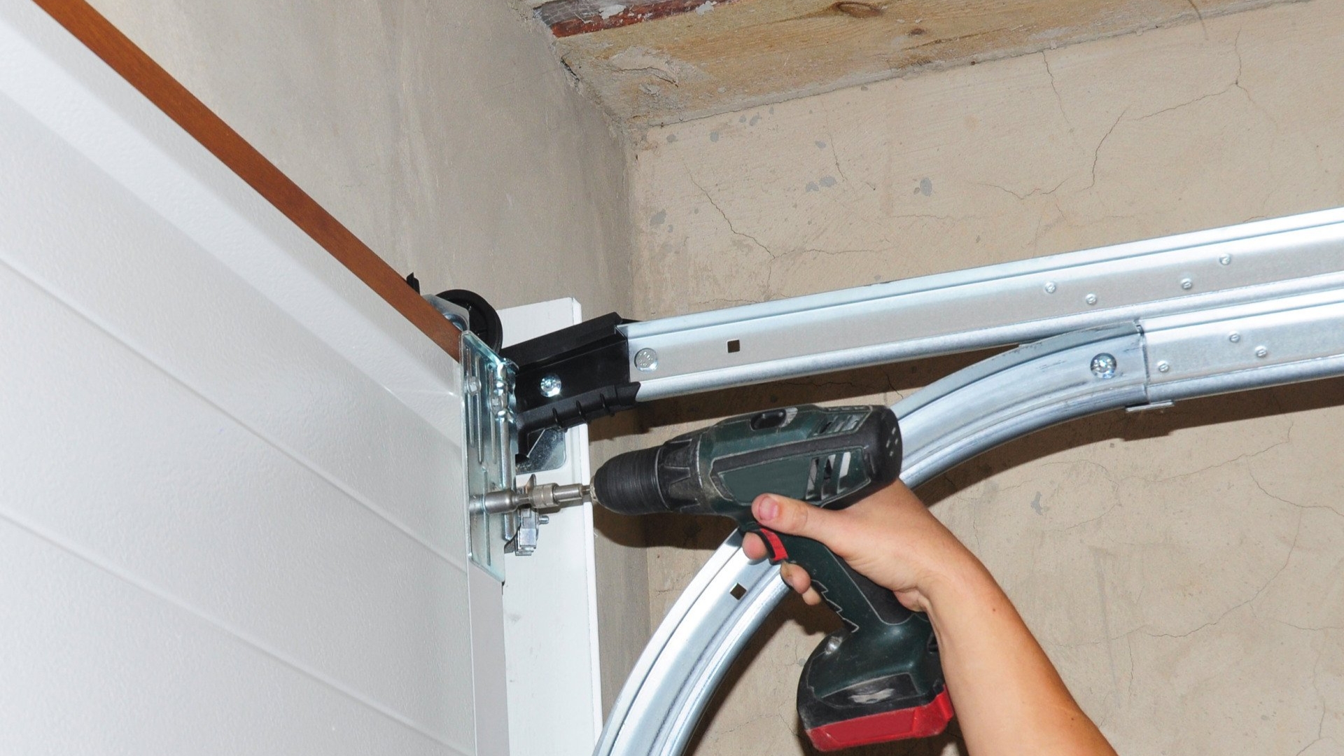 A technician tightening the loose garage door hardware