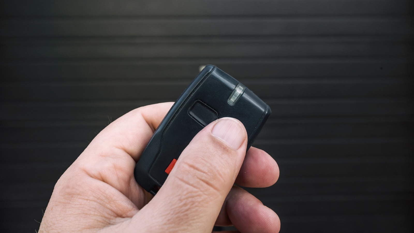A man holding a garage door remote control in front of the door