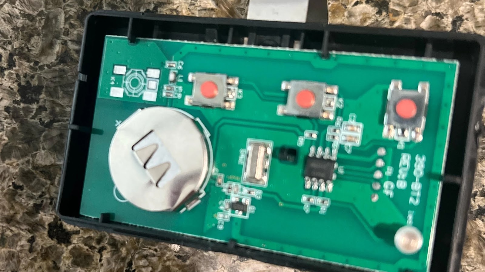 An open garage door remote showing its components and battery