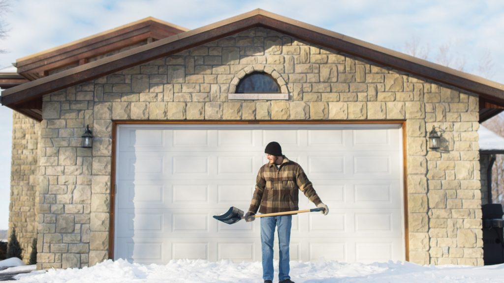 A man shoveling snow in front of his garage door in Omaha