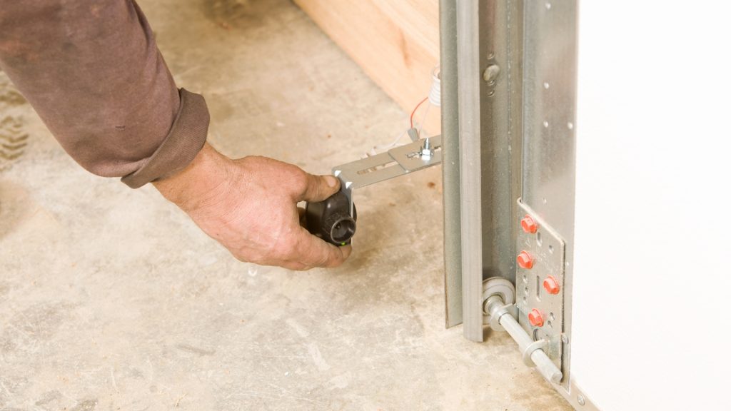 A man adjusting the safety sensors due to a garage door reversing problem