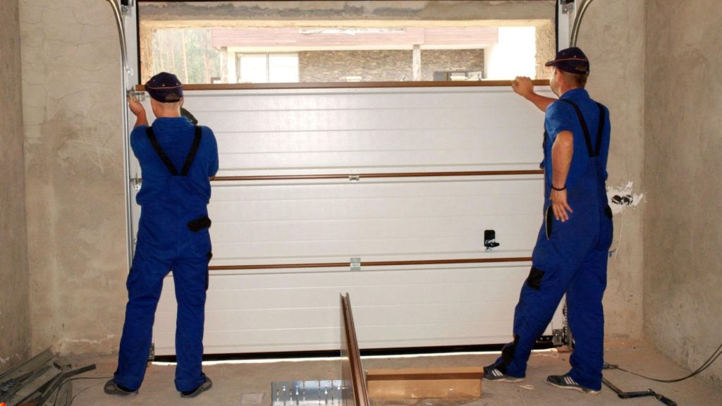 Garage door technicians installing a new sectional garage door in a residential home