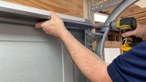 Technician reinforcing a garage door using a power drill, an important step in preventing garage break-ins